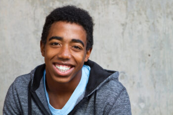 Smiling teen boy on grey background