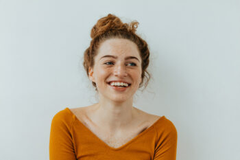 Freckled girl smiling on grey background