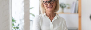 Portrait of smiling senior businesswoman in glasses standing posing in modern office, happy confident middle-aged female employee or CEO look at camera show confidence and success at workplace